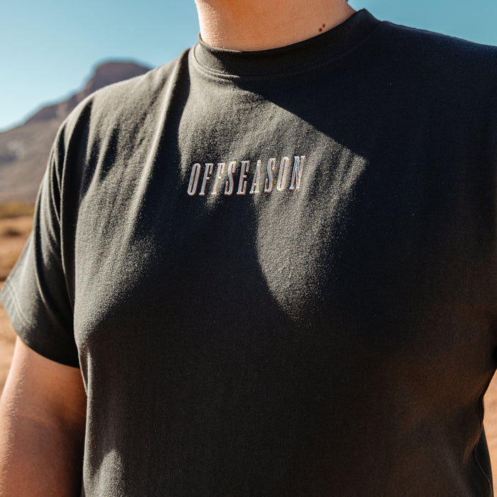Adult model wearing black graphic tee with “Backstop Range Relaxed” design
