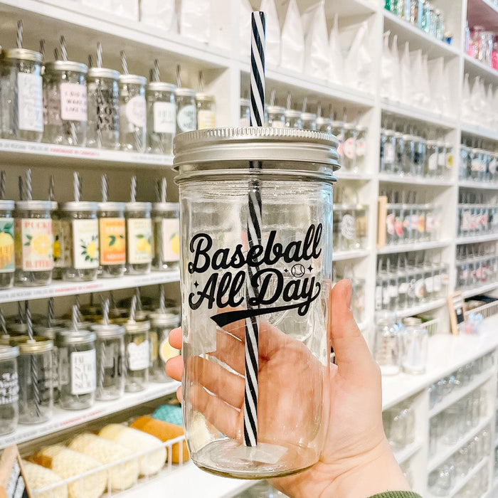 Hand holding a mason jar tumbler that reads baseball all day in black text on clear background