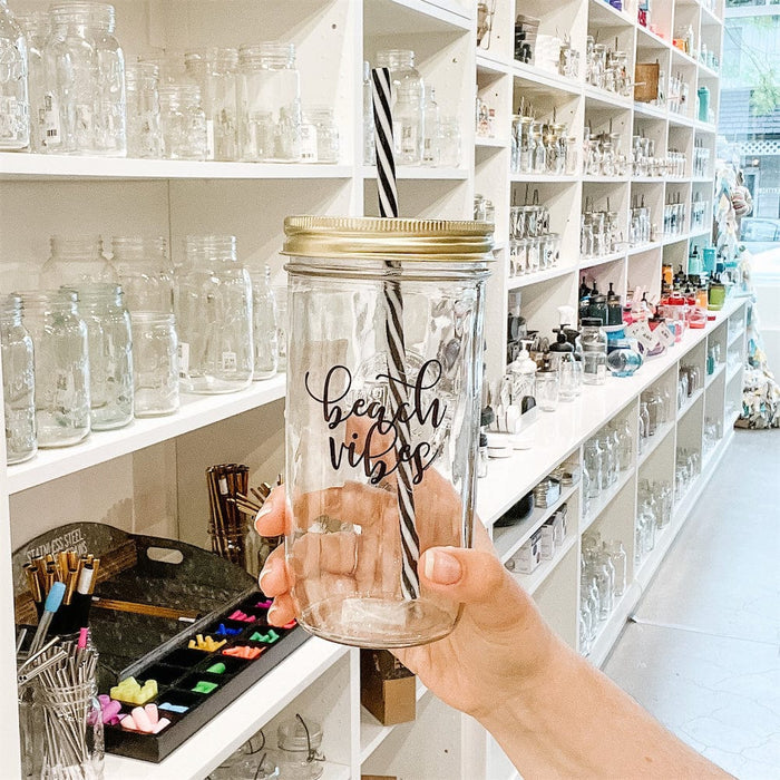 A photo of a mason jar tumbler with a sticker text that says "Beach Vibes"