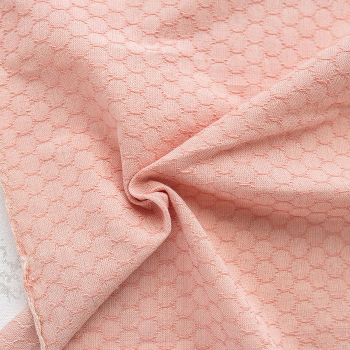 Close-up of pink textured fabric with a subtle honey comb pattern