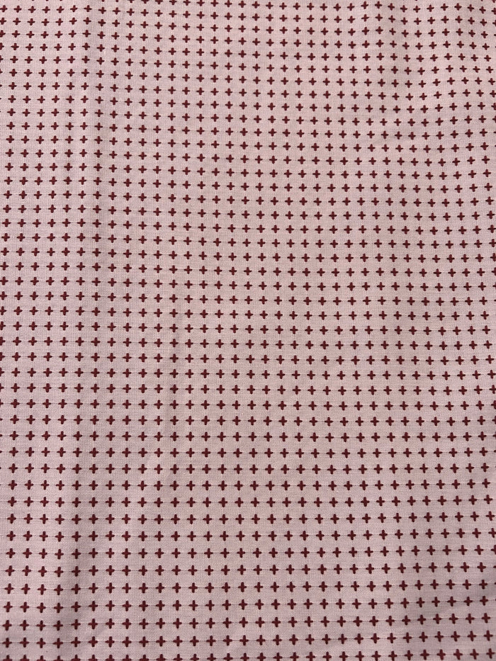 Patterned fabric with small crosses on a pink background