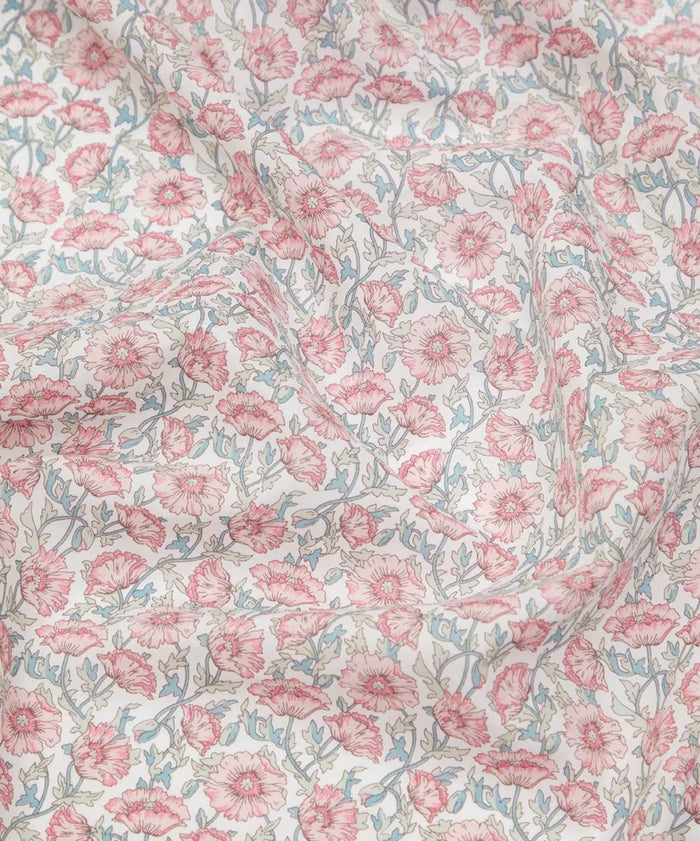 Draped Liberty of London cotton tana lawn in a beautiful, vibrant print of pink poppies with blue stems on a white background.