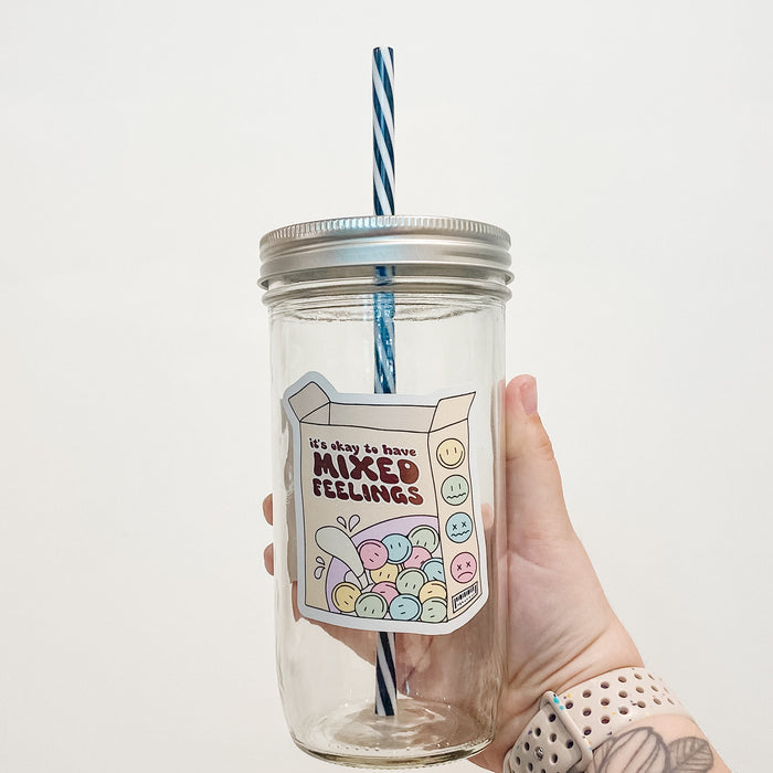 Hand holding a mason jar that reads mixed feelings as a box of cereal, the different expressions being the cereal.
