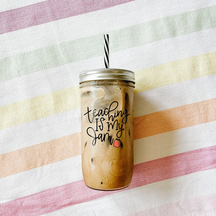 Tumbler with iced coffee with print that says "Teaching is my jam" with a jam beside the text as a design. Photographed against a backdrop of a striped fabric..