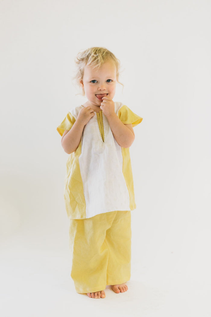 Small child wearing a yellow and white Turkish tunic and yellow pants.