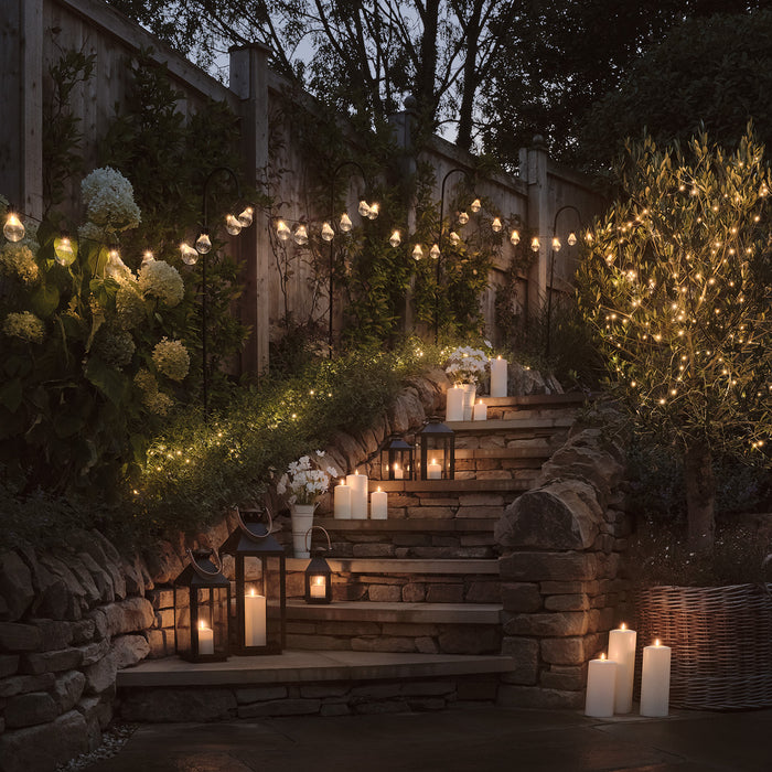 Festoon lights hanging above garden steps with LED candles and lanterns