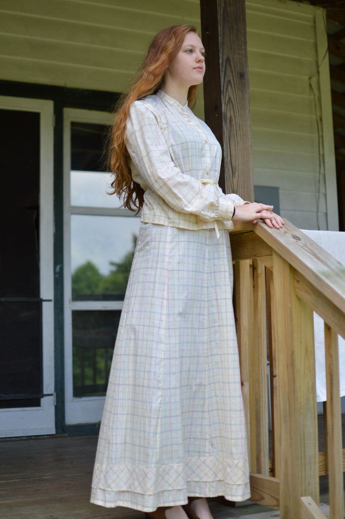 Young red head woman standing on a porch wearing 216 Schoolmistresses Shirtwaist and Skirt.