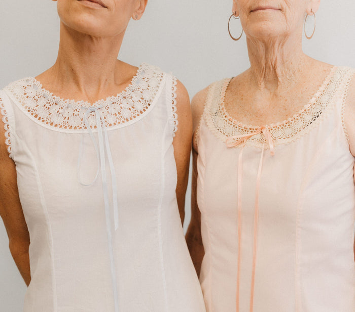 Close up of the top of two slips with lace at the necklines.