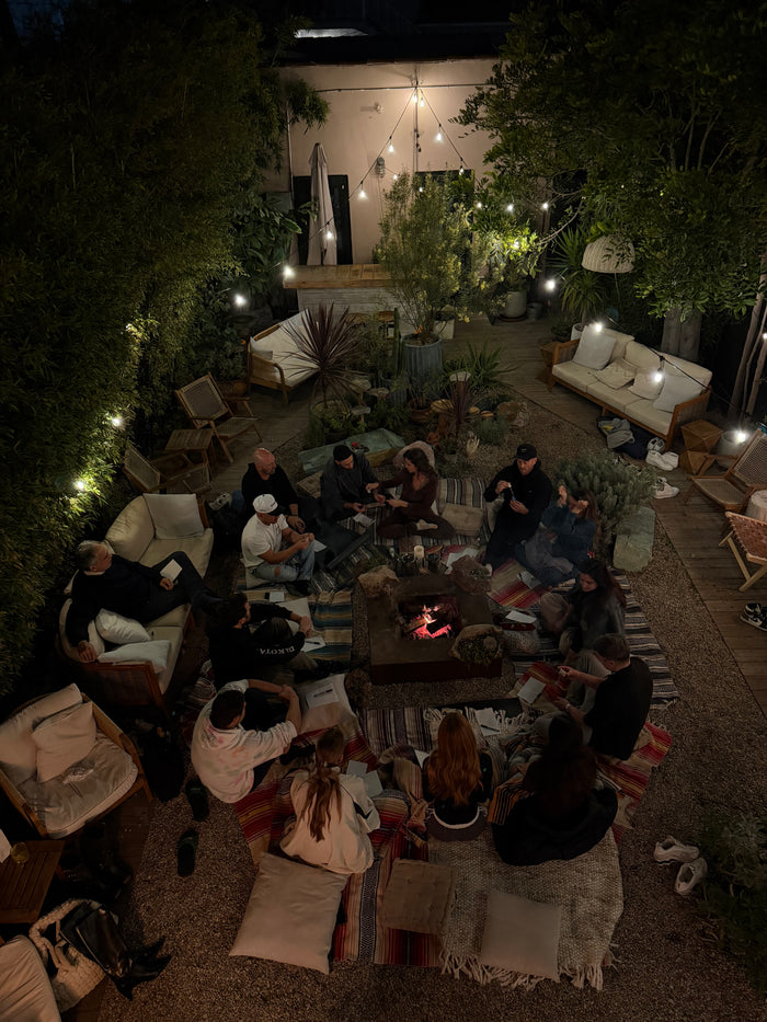 People gathered around a fire pit in an outdoor setting with string lights and furniture.