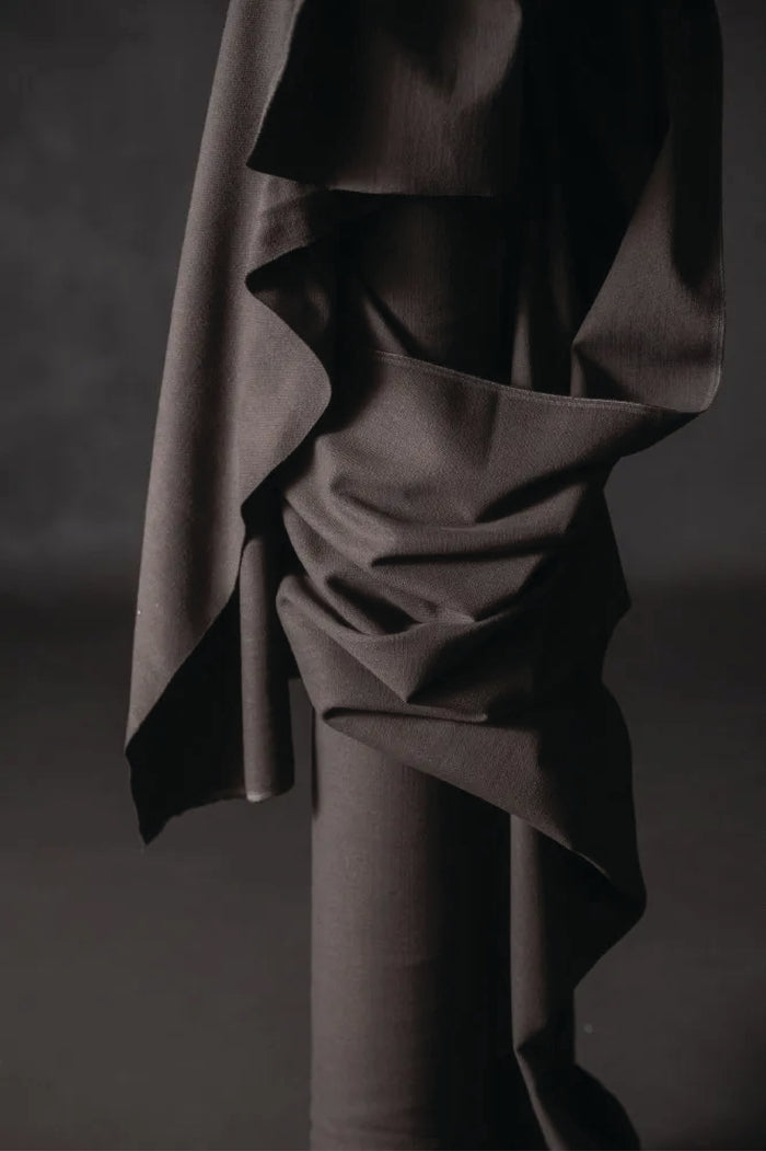 Cotton canvas fabric is a warm charcoal color. draped over a cylindrical object against a dark background.
