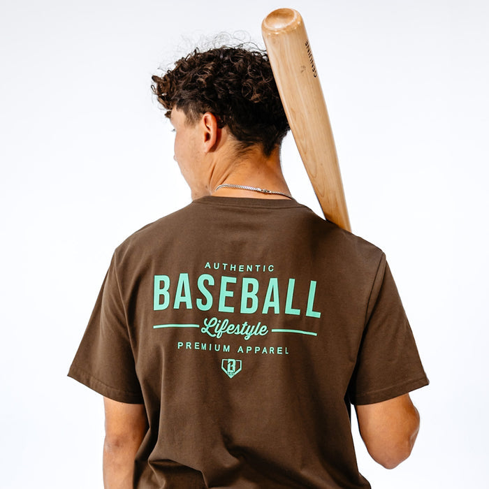 Person wearing a brown 'Baseball Lifestyle' t-shirt holding a baseball bat on a white background