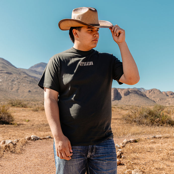 Adult model wearing black graphic tee with “Backstop Range Relaxed” design