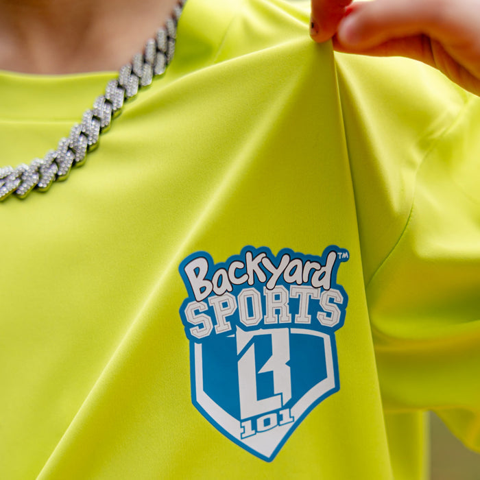 Adult model wearing yellow graphic tee with “Ballpark Lights Athletic” design