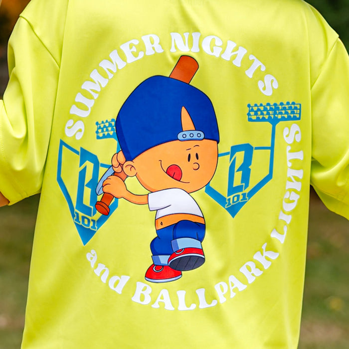Adult model wearing yellow graphic tee with “Ballpark Lights Athletic” design