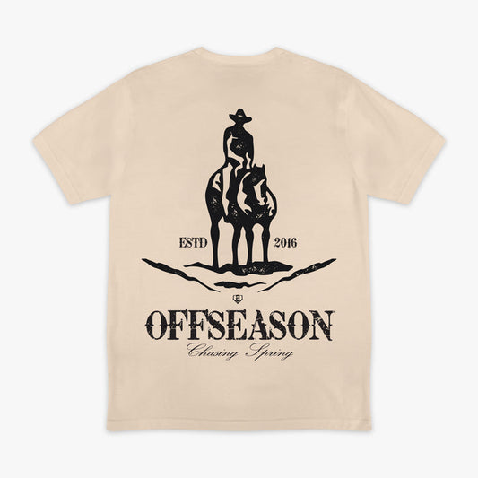 Beige t-shirt with a graphic of a person on a horse and text 'Offseason Chasing Spring' on a white background