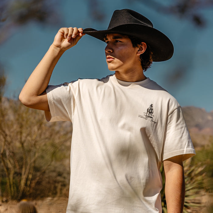 Adult model wearing white graphic tee with “Bat and Bridle Relaxed” design