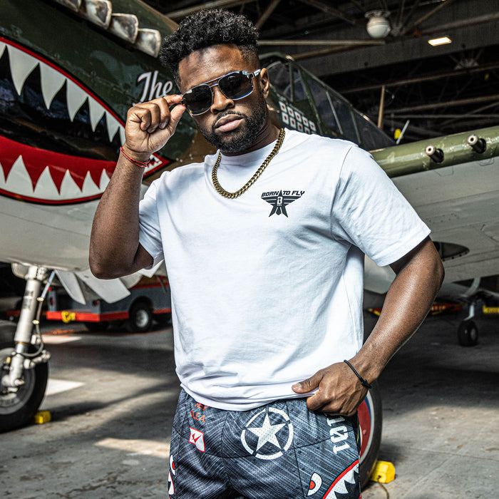 White t-shirt with black “BORN TO FLY” lettering, black star, and white BL101 logo inside the star positioned on the top corner of the shirt on person