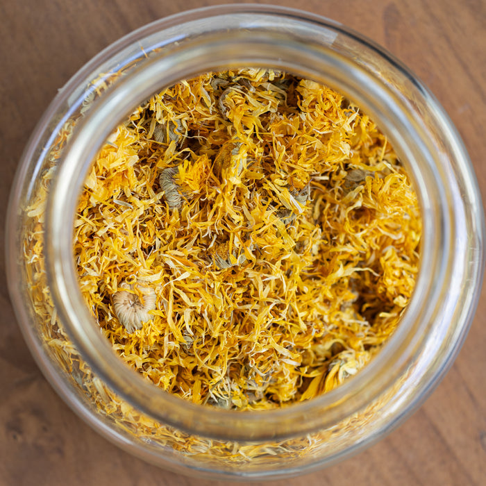 Glass jar filled with yellow dried herbs on a wooden surface