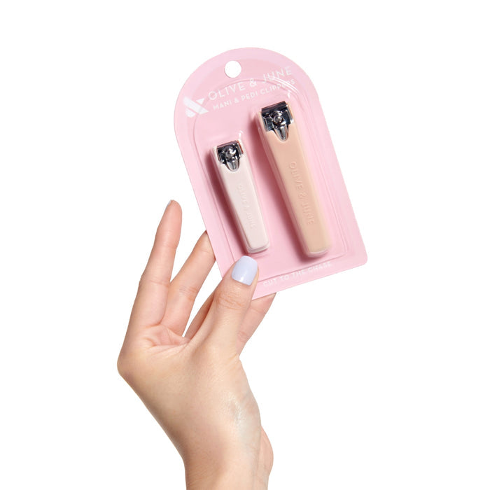 Hand holding Olive and June Clipper Set with flat-edge mani and pedi clippers in neutral tones for nail care