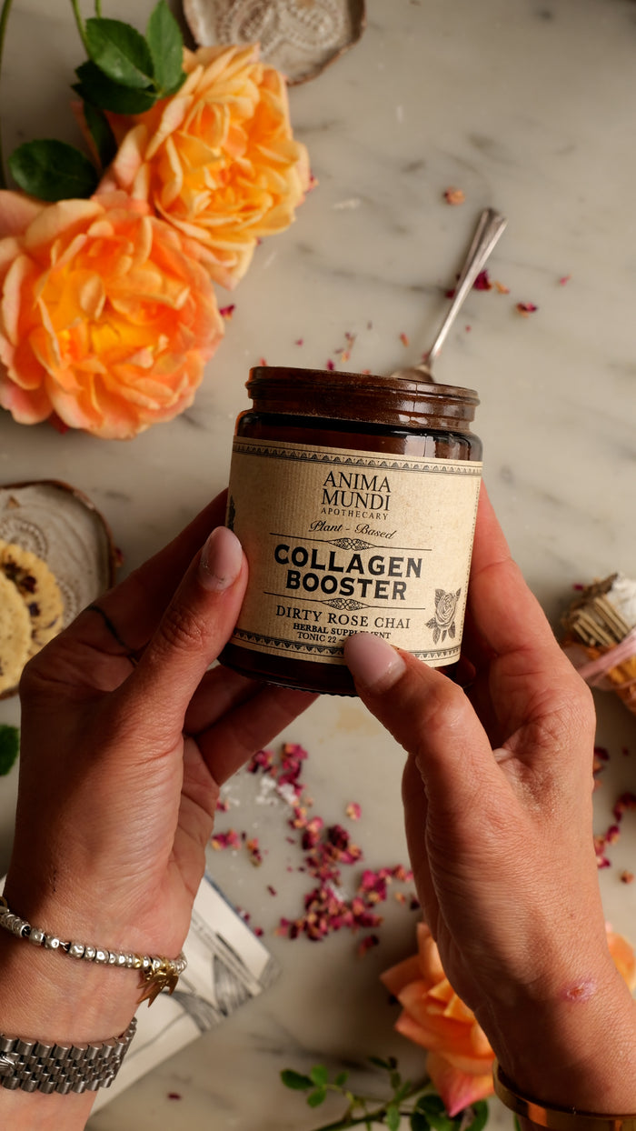 Person holding a jar of 'Anima Mundi' collagen booster with flowers in the background