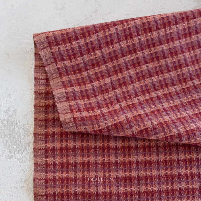 Folded fabric with a checkered pattern on a light background, featuring the brand 'Fablism'.