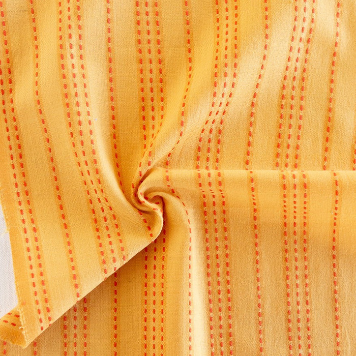 Close-up of yellow fabric with red stitching