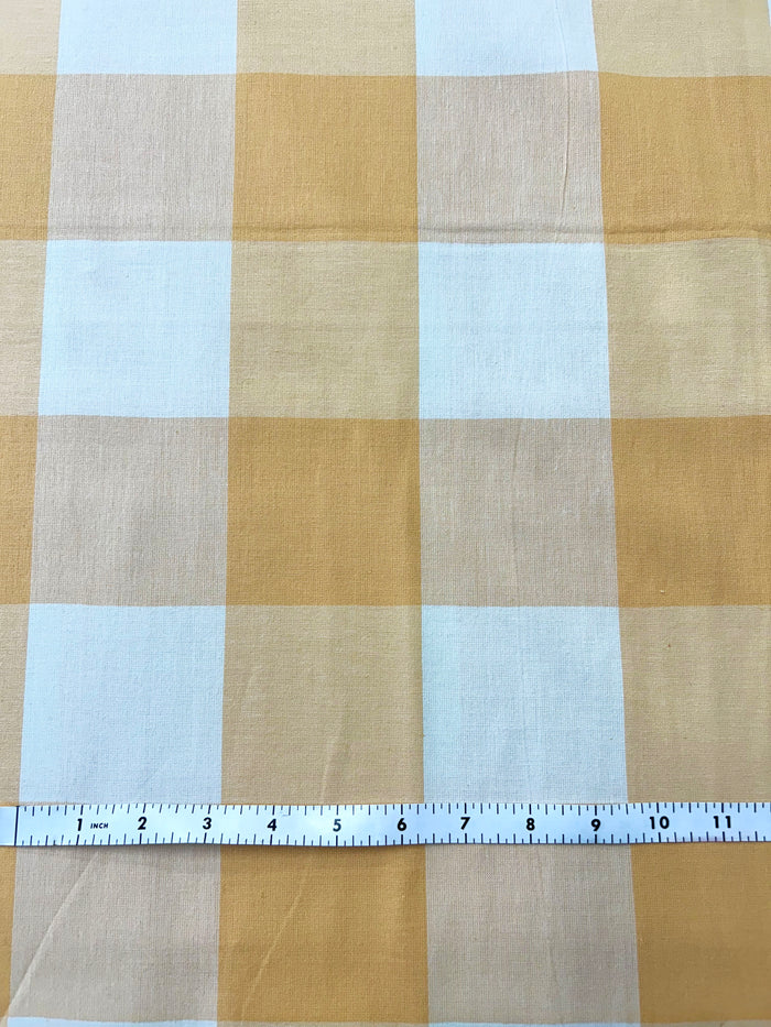 Checkered fabric of yellow and white  with a ruler at the bottom for scale.