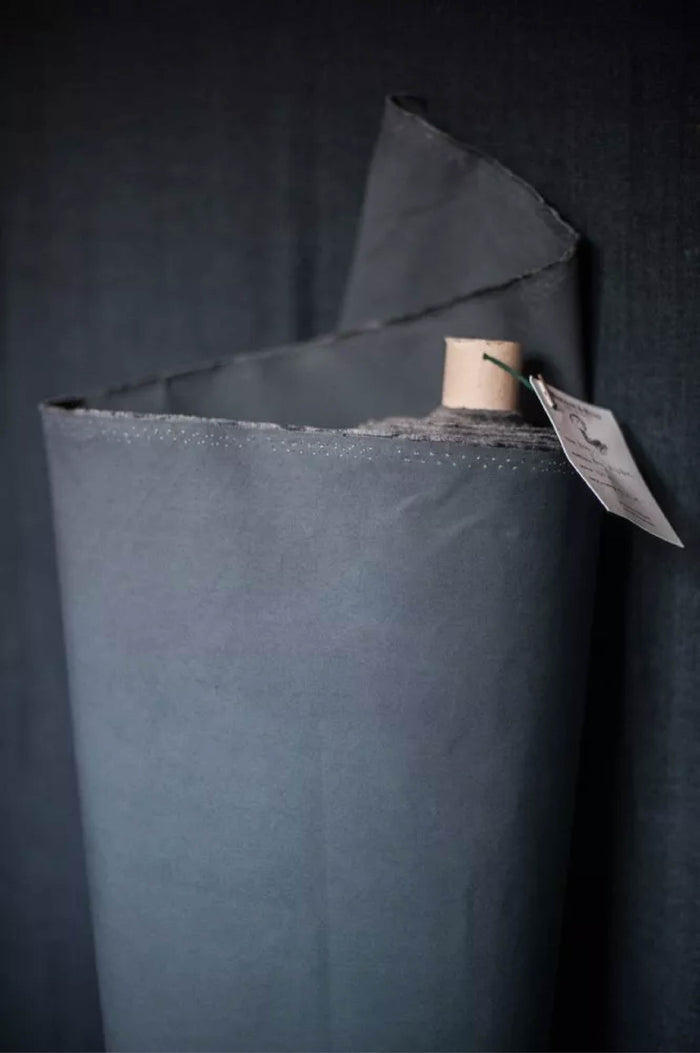 Roll of black fabric with a tag on a dark background