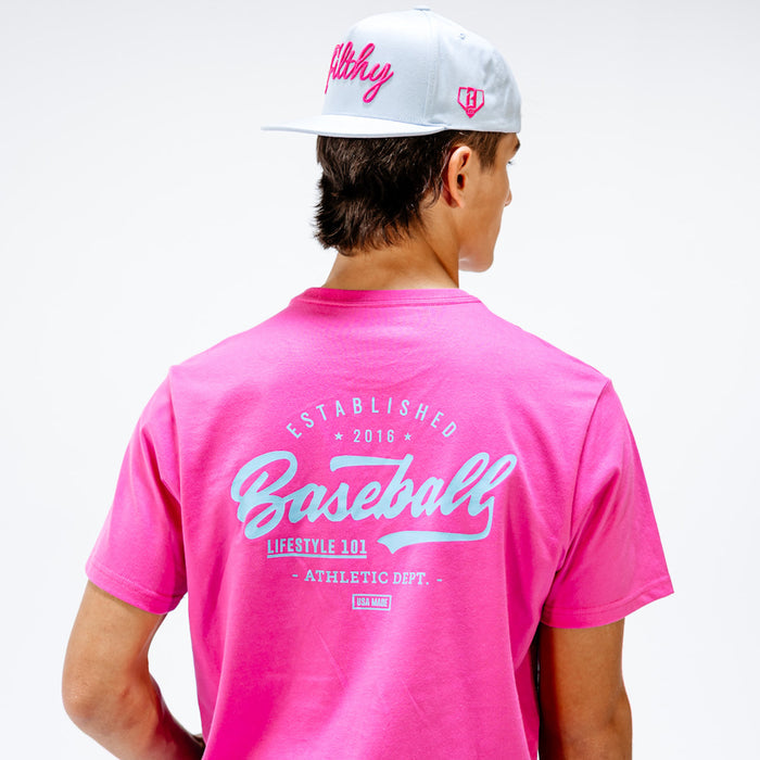 Person wearing a pink t-shirt with text 'Established 2016 Baseball Lifestyle 101 Athletic Department' and a white cap on a light gray background