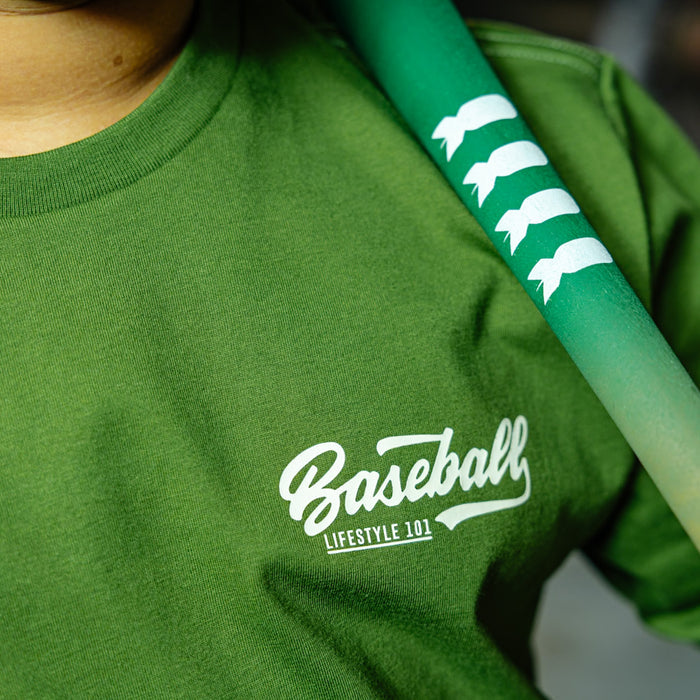 Close up of Olive green baseball graphic Youth T- Shirt with vintage white lettering that says 'Baseball Lifestyle 101' in top corner on person