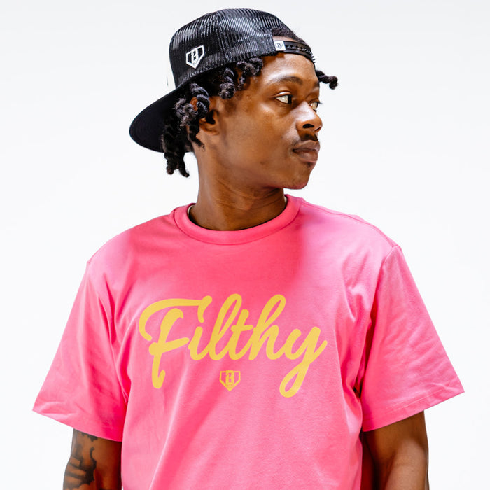 Person wearing a pink t-shirt with yellow 'Filthy' text printed on it and a black cap.