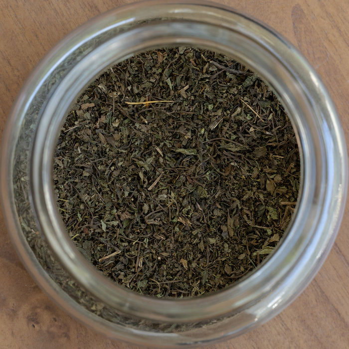 Glass jar filled with dried herbs on a wooden surface