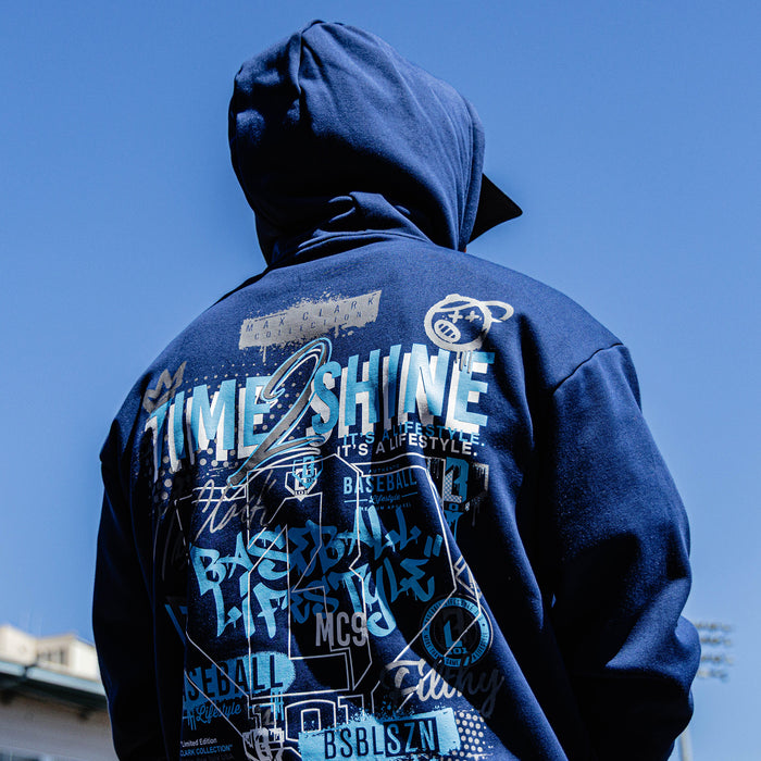 Person wearing a blue hoodie with text and graphics on the back against a clear blue sky.