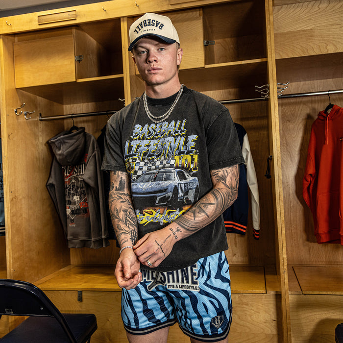 Man wearing a black t-shirt with graphics and blue shorts in a locker room.
