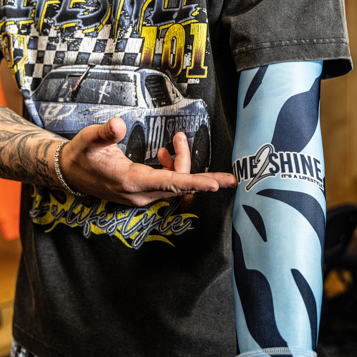 Person wearing a graphic t-shirt with car design and colorful leggings with 'Me 2 Shine' text.