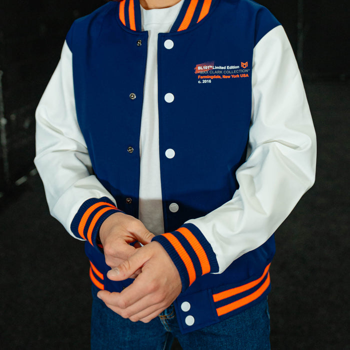Person wearing a blue and white varsity jacket with orange accents on a black background