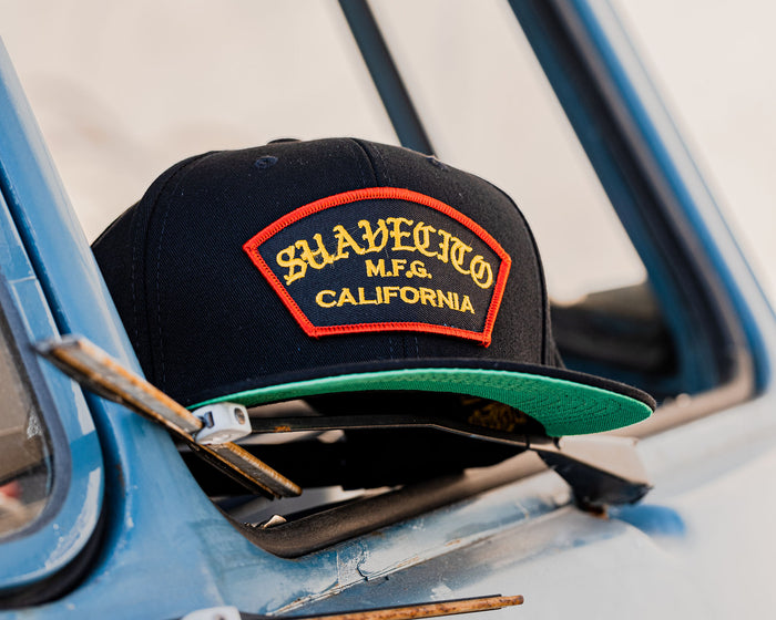 suavecito hat with yellow embroidered text and red border outline "suavecito m.f.g. california"