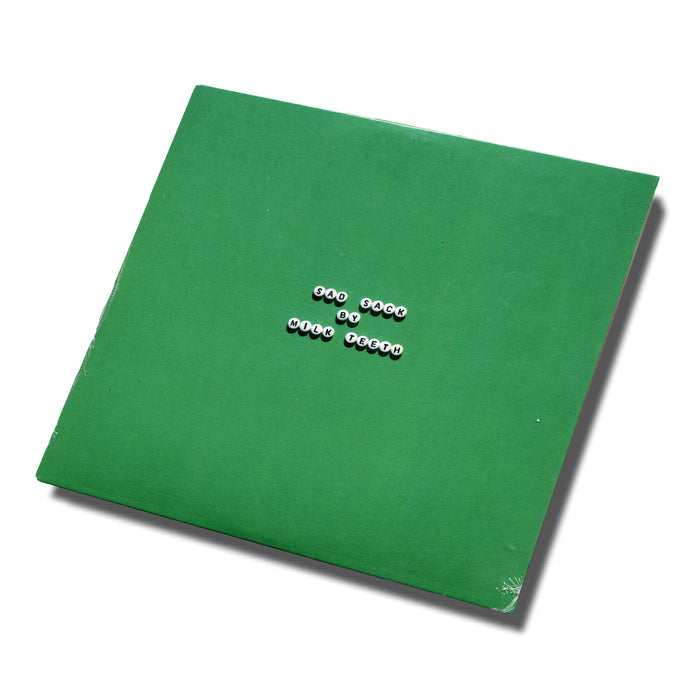 A green square album cover with white beads spelling one book by wolf tycoon in the center, set on a white background with a slight shadow—ideal for fans of the brand Milk Teeth or anyone interested in the CD tracklist.