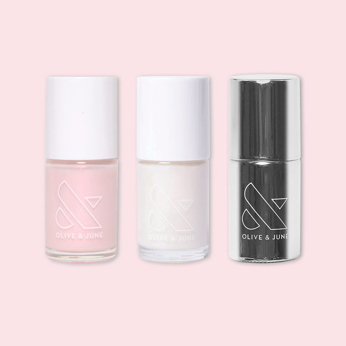 Mother of Pearl nail polish set by Olive and June featuring soft pink, pearly white, and glossy top coat bottles on pink background