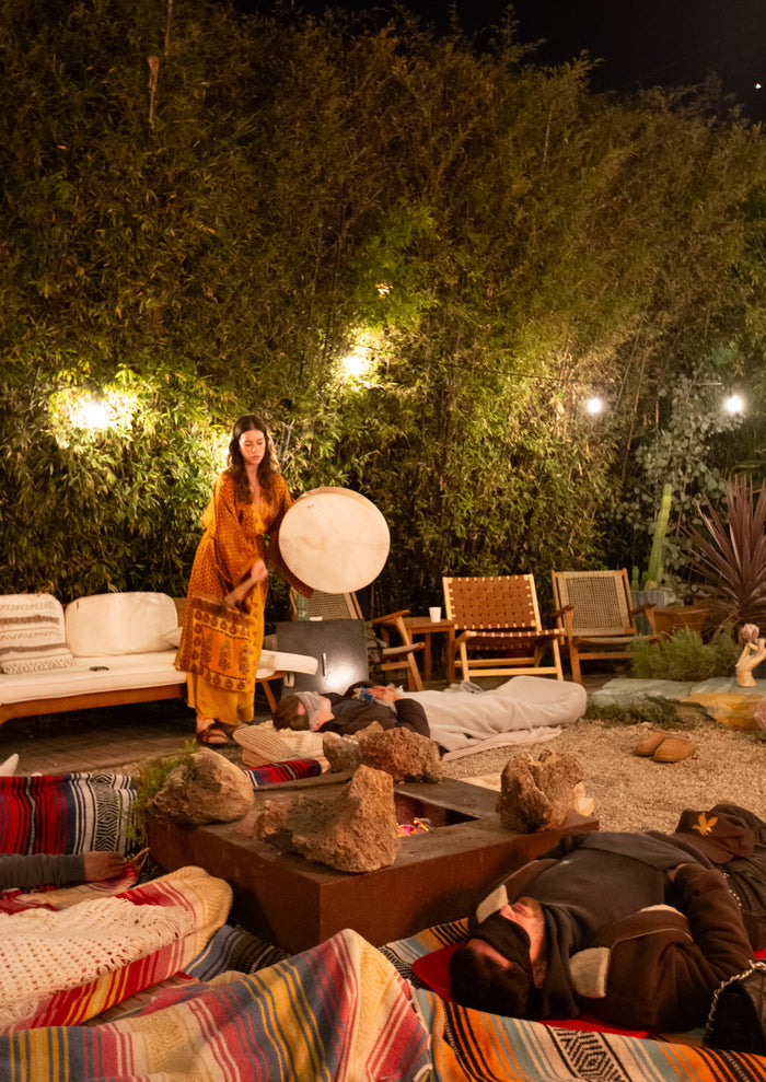 Woman standing in a garden setting with outdoor furniture and lighting