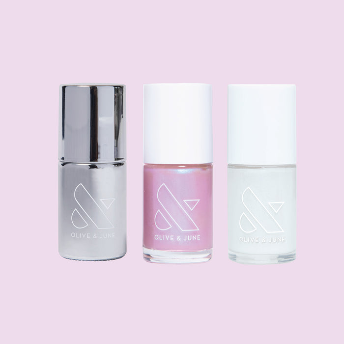 Three nail polish bottles in metallic, pink, and iridescent shades from Olive and June’s Pink Opal Set for manicures