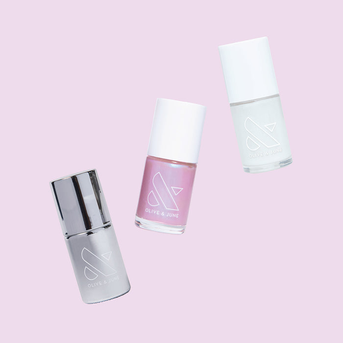 Three nail polish bottles in soft pink and metallic shades from Olive and June’s Pink Opal Set for manicures