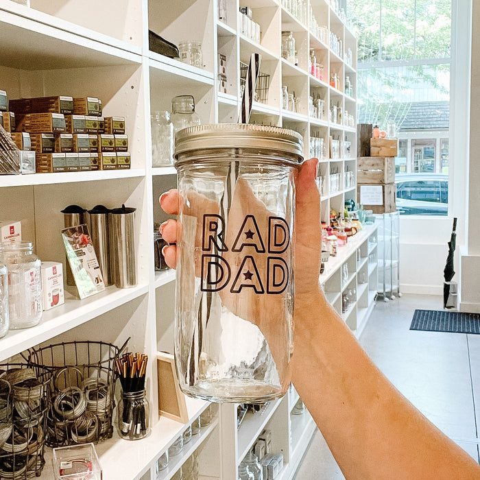 hand holding a mason jar tumbler that says "RAD DAD"