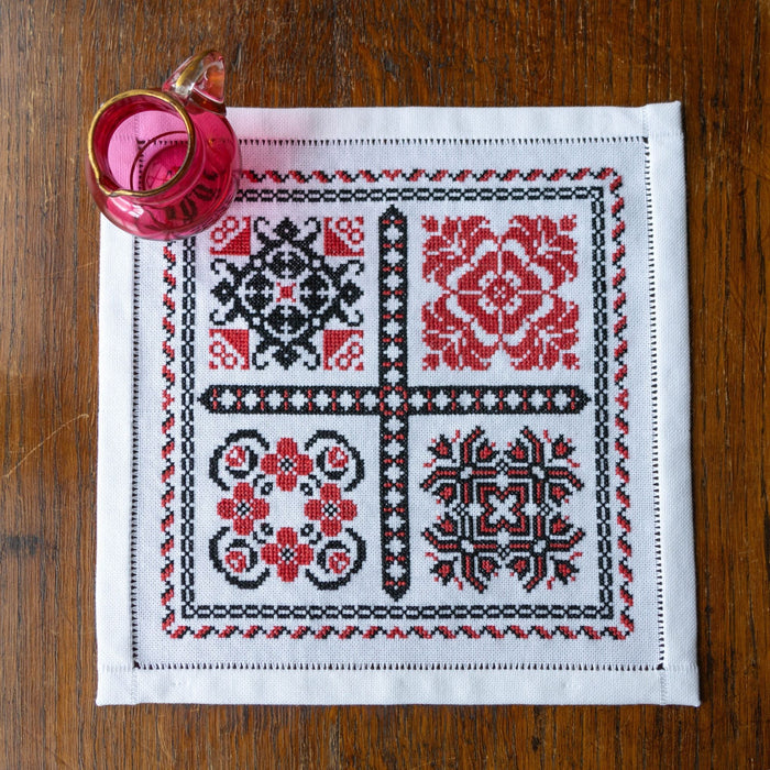 Embroidered placemat with floral patterns on a wooden surface