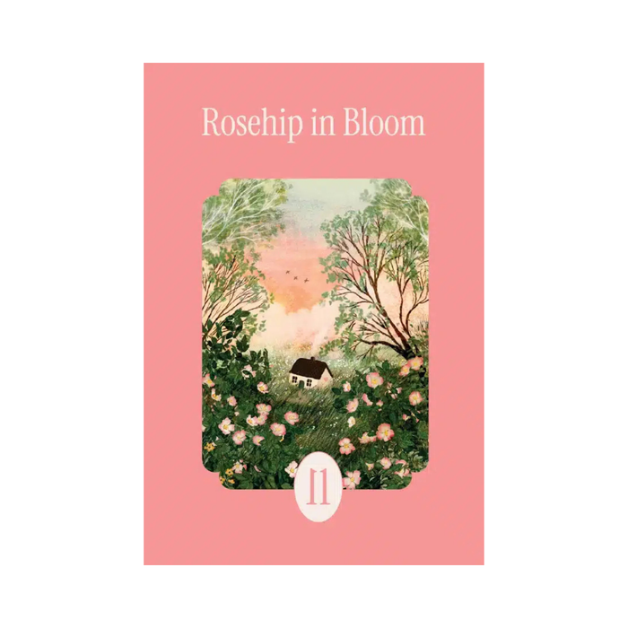 Rosehip in Bloom | 99 Piece Jigsaw Puzzle by la pauz features artwork by Laivi Põder, depicting a captivating scene of a small house nestled among blooming rose bushes and trees under a sunset sky. The pink card displays the number 11 at the bottom and beautifully showcases this enchanting mini puzzle.