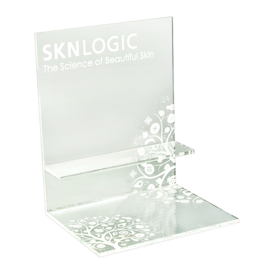 SKN041 SKNLOGIC Clear Acrylic Product Display Stand | Clear acrylic skincare display stand with frosted branding that reads 'SKNLOGIC The Science of Beautiful Skin' and white floral scrollwork, shown on a plain white background.