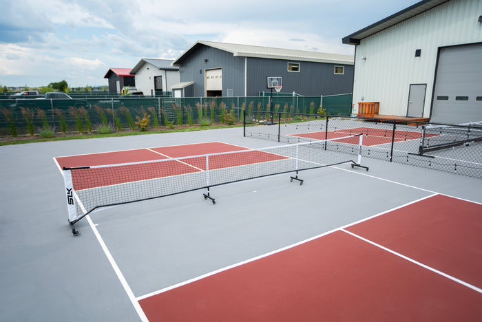 SLK Prime Portable Pickleball Net with wheels set up on outdoor courts