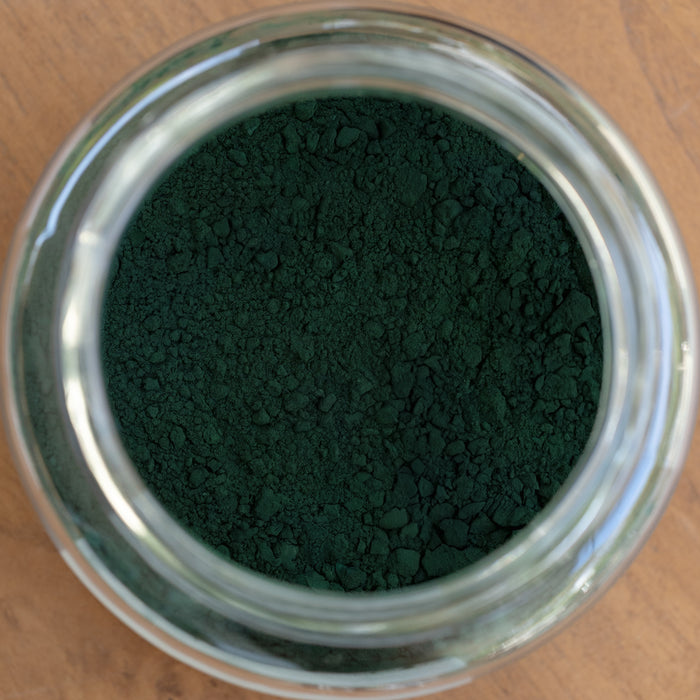 Close-up of a glass jar filled with green powder on a wooden surface