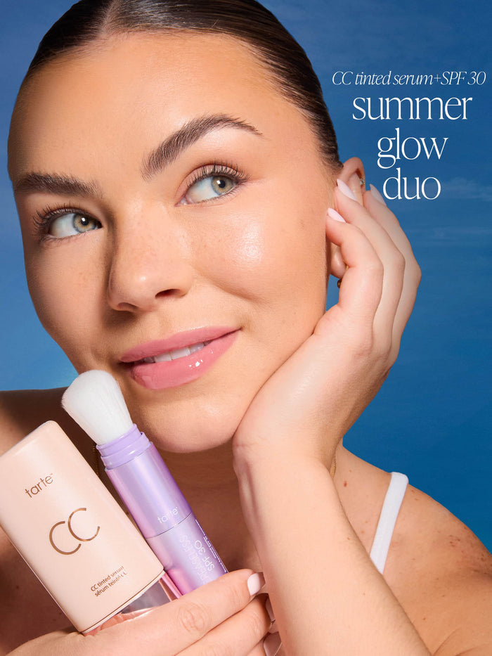 Woman holding tarte CC tinted serum with a blue background