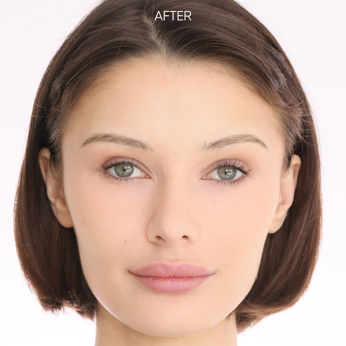 Woman applying skincare product with a brush on a neutral background